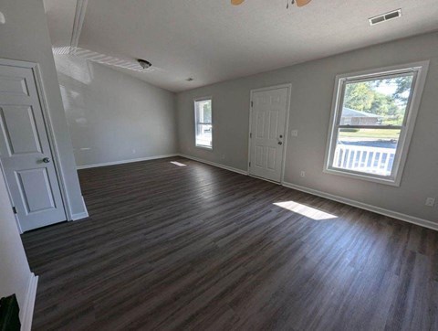 A room with wooden flooring and white walls.